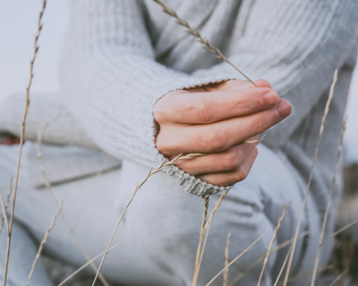 person sitting in grass holding a piece of nature wearing a cozy sweater peaceful moment relaxation mindfulness in nature