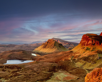 scenic landscape with mountains and water showing five distinct geological formations and colors at sunset